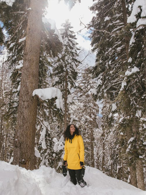 Woman in a Yellow Jacket Enjoying the Snow Covered Trees