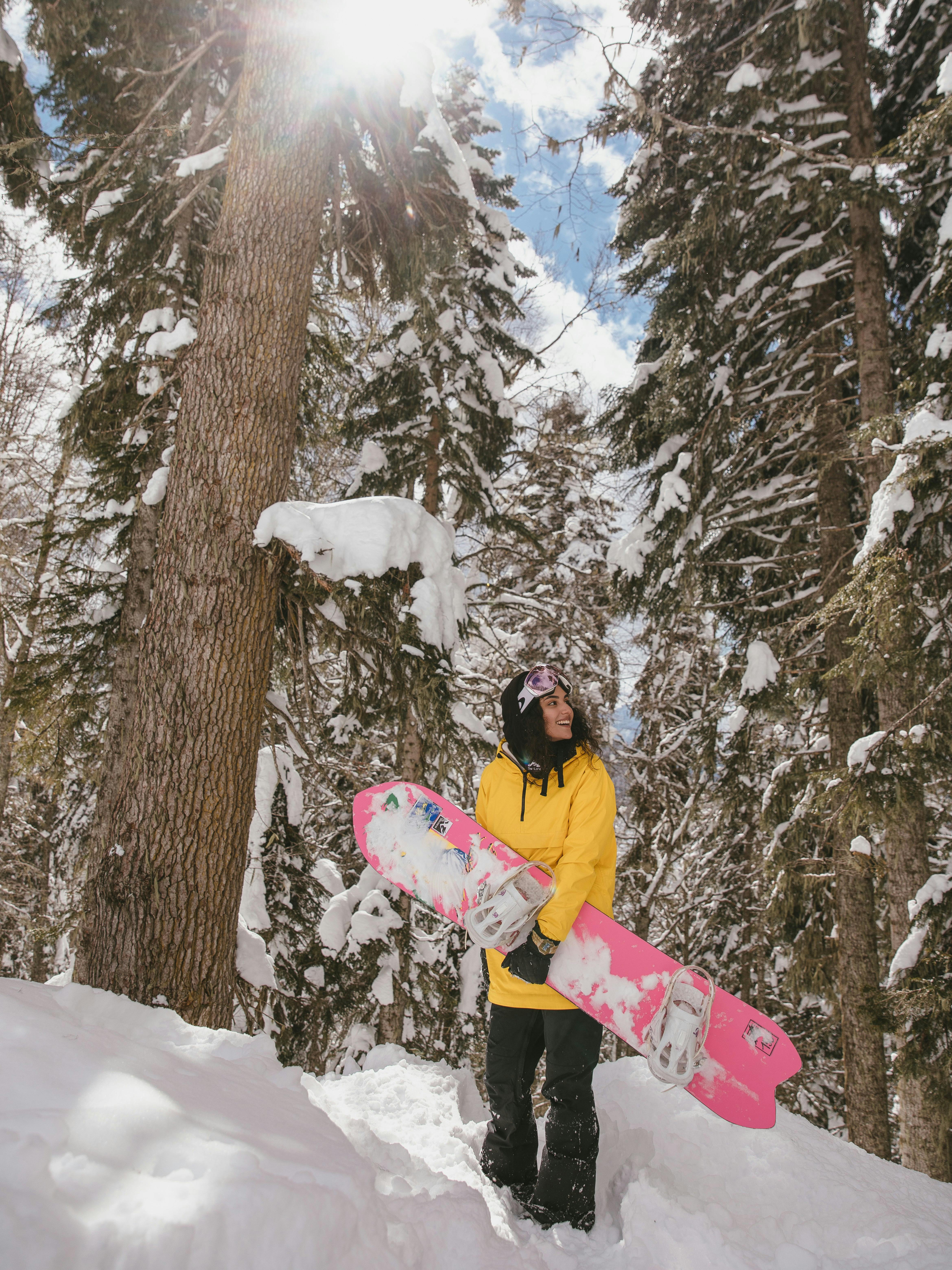 Prescription Goggle Inserts - A woman with snowboard in winter forest, enjoying a sunny day on snowy terrain.