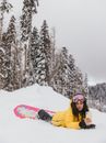 Woman in Yellow Winter Jacket Lying Down on the Snow-Covered Ground while Taking a Selfie