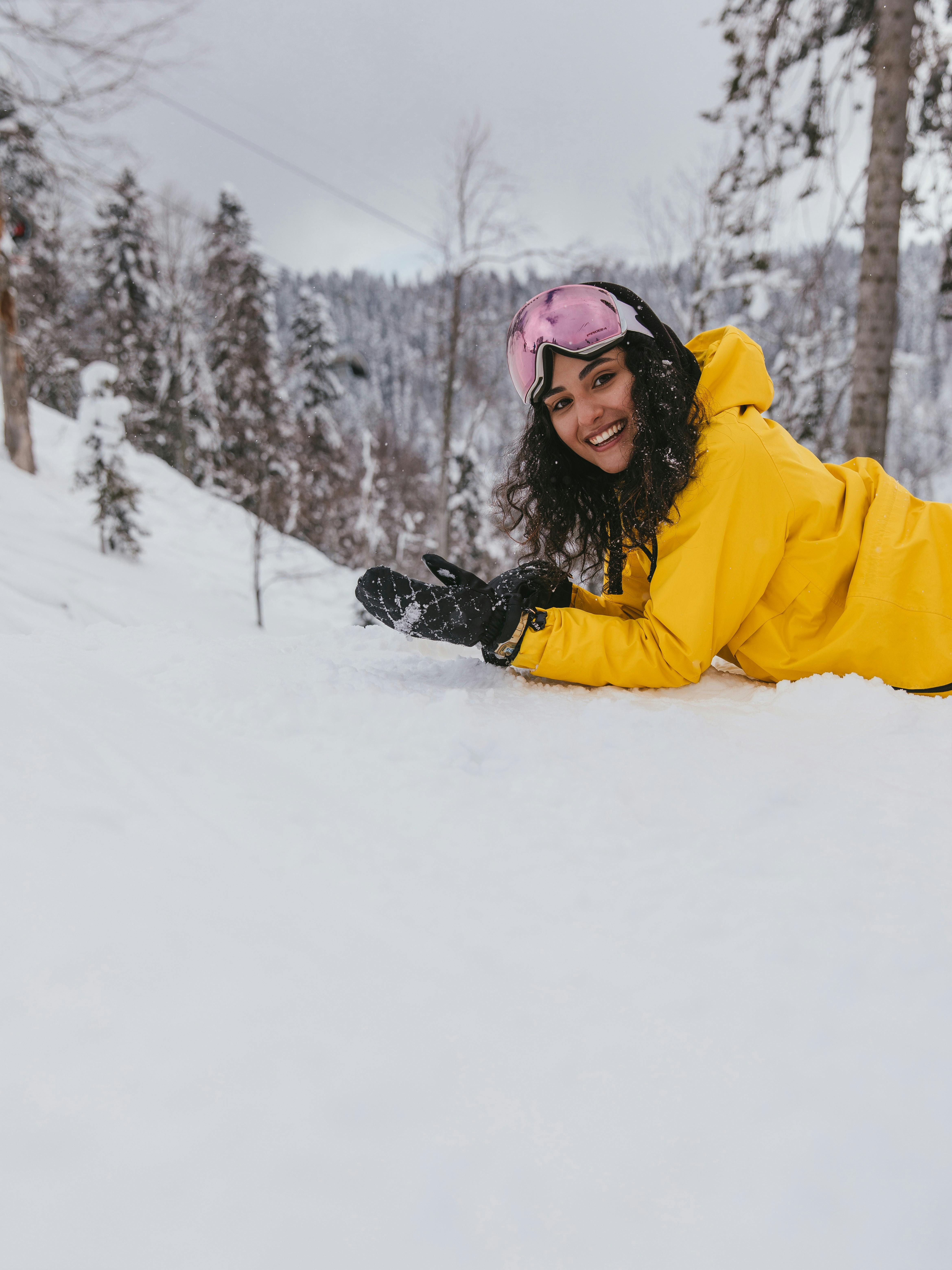 Prescription Goggle Inserts - Smiling woman in winter clothing lying on snow-covered ground outdoors.