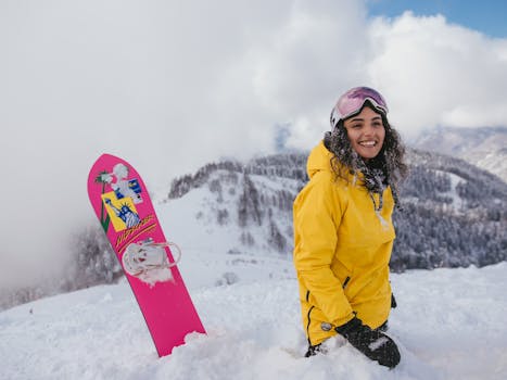 A joyful woman with a snowboard, enjoying winter in the snowy mountains.