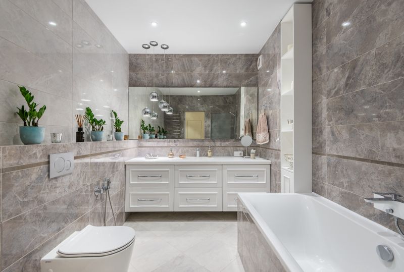 Spacious marble bathroom with bathtub and round mirror
