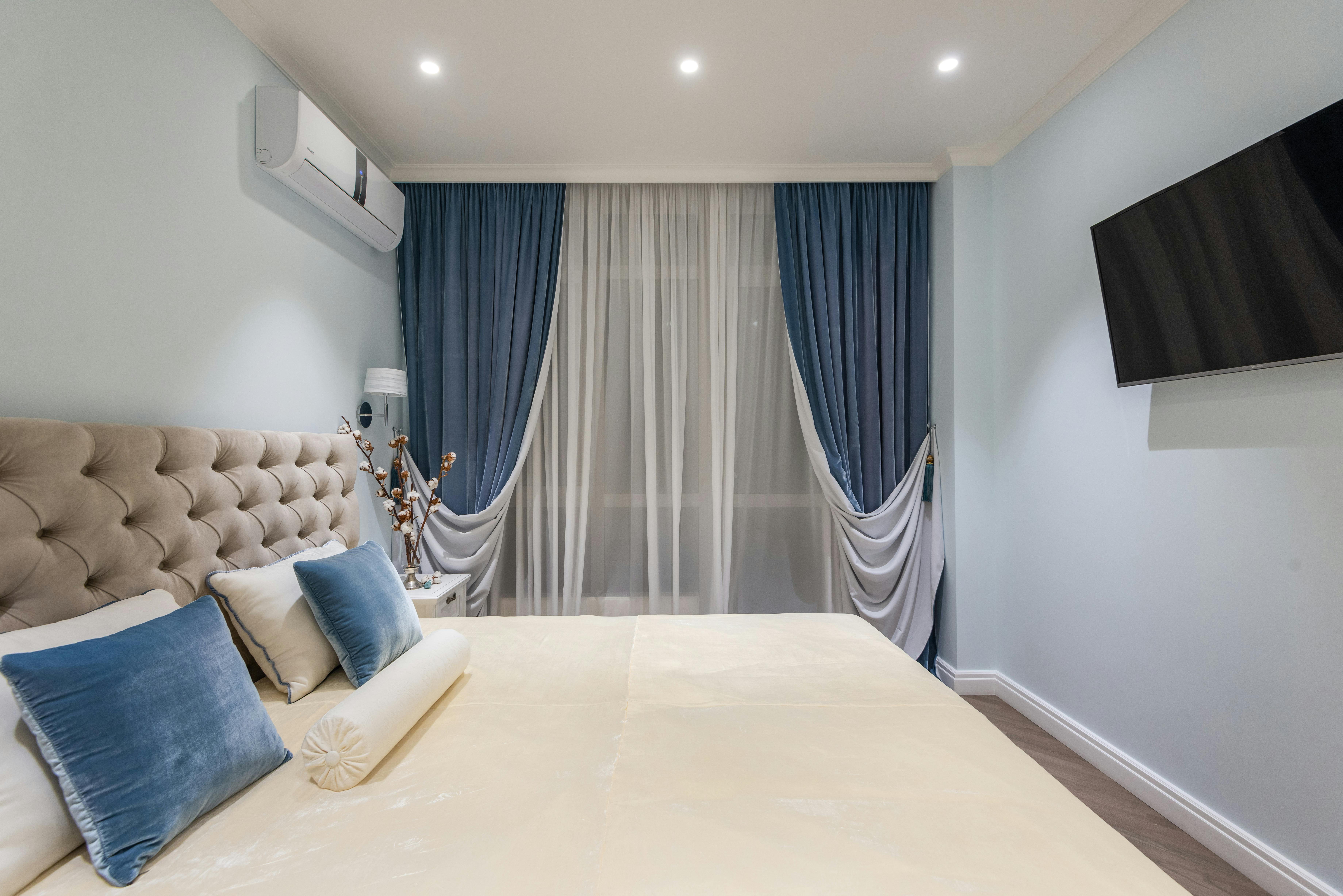 interior of cozy bedroom with soft bed and blue cushions and curtains