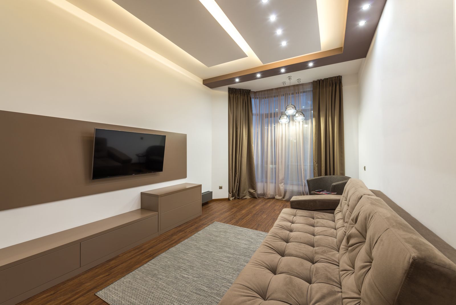Living room with a designed false ceiling and integrated cove lighting