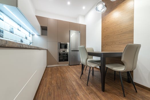 Sleek modern kitchen with dining area, featuring neutral tones and minimalist design.