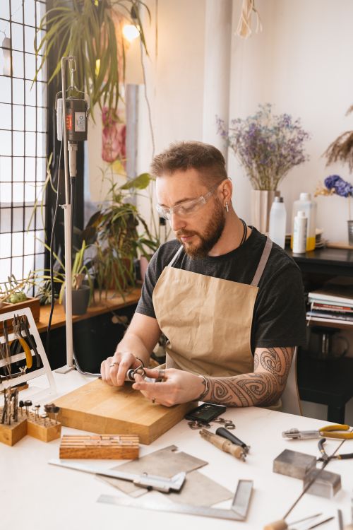 Free Artisan creating jewelry pieces at a well-equipped workbench with tools. Stock Photo