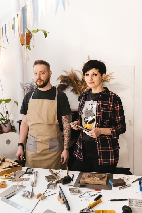 Free Two adults crafting in a bright workshop with woodworking tools and materials. Stock Photo