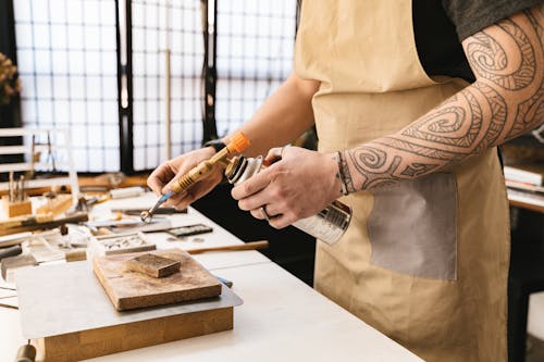 A Person Holding a Blowtorch and a Tweezer with a Metal Ring