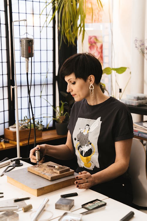 A Woman Sitting at the Work Desk Holding a Blowtorch