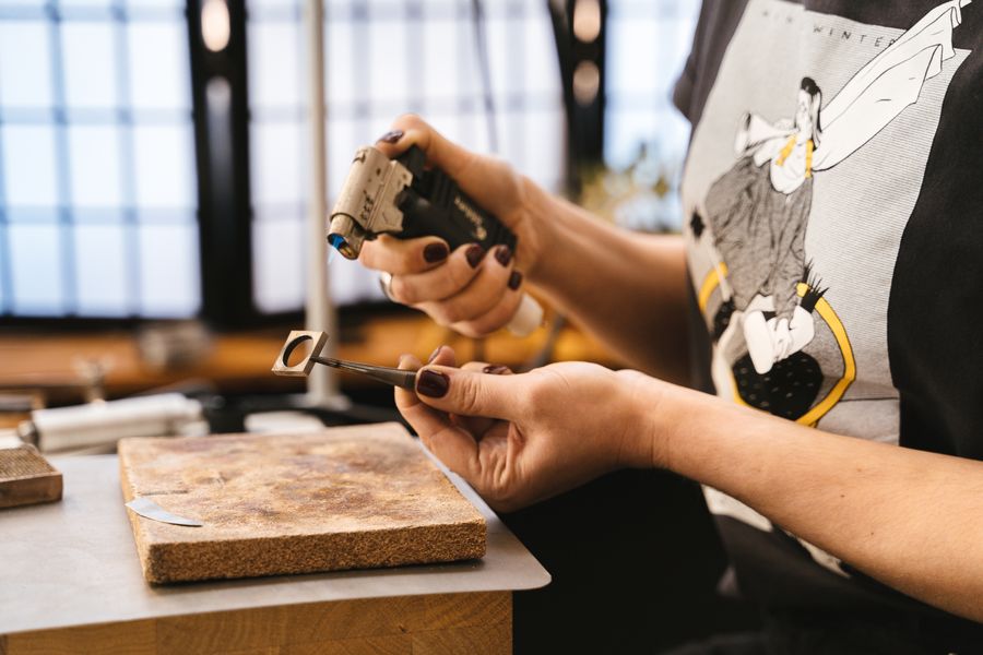 Artisan crafting jewelry with tools in a workshop