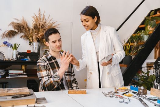 Two adults collaborating on a jewelry project in a modern indoor workspace.
