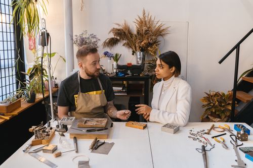 Free Man and woman discussing jewelry design in an artisan studio. Stock Photo