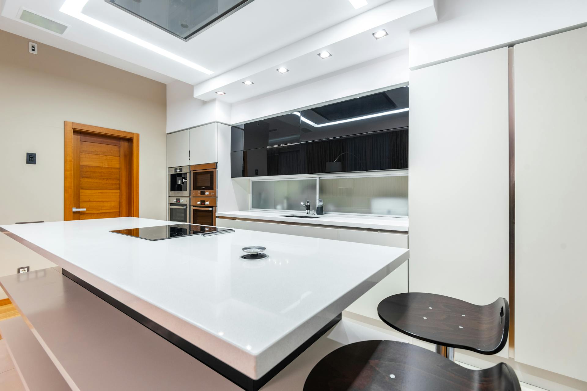 Contemporary kitchen interior featuring minimalist design, induction hob, and high stools.