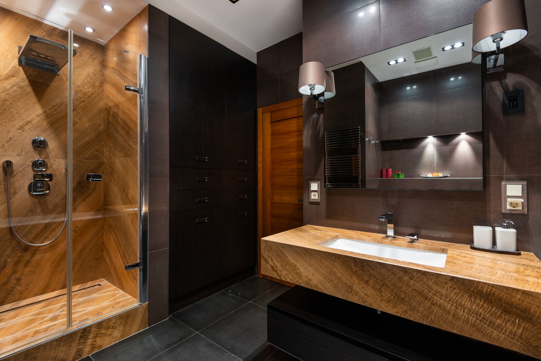 Contemporary bathroom with warm wood elements and dark architectural surfaces