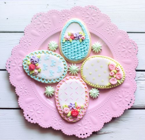 Free Colorful Easter cookies with royal icing decorations on a pink doily plate. Stock Photo
