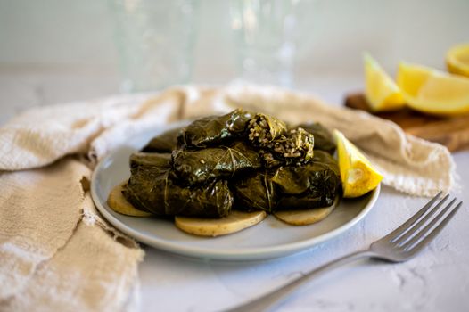 Close-up of stuffed grape leaves on a plate with lemon slices, perfect for a Mediterranean meal.