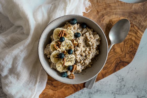 Bowl of oatmeal topped with banana slices, pecans, blueberries and chia seeds