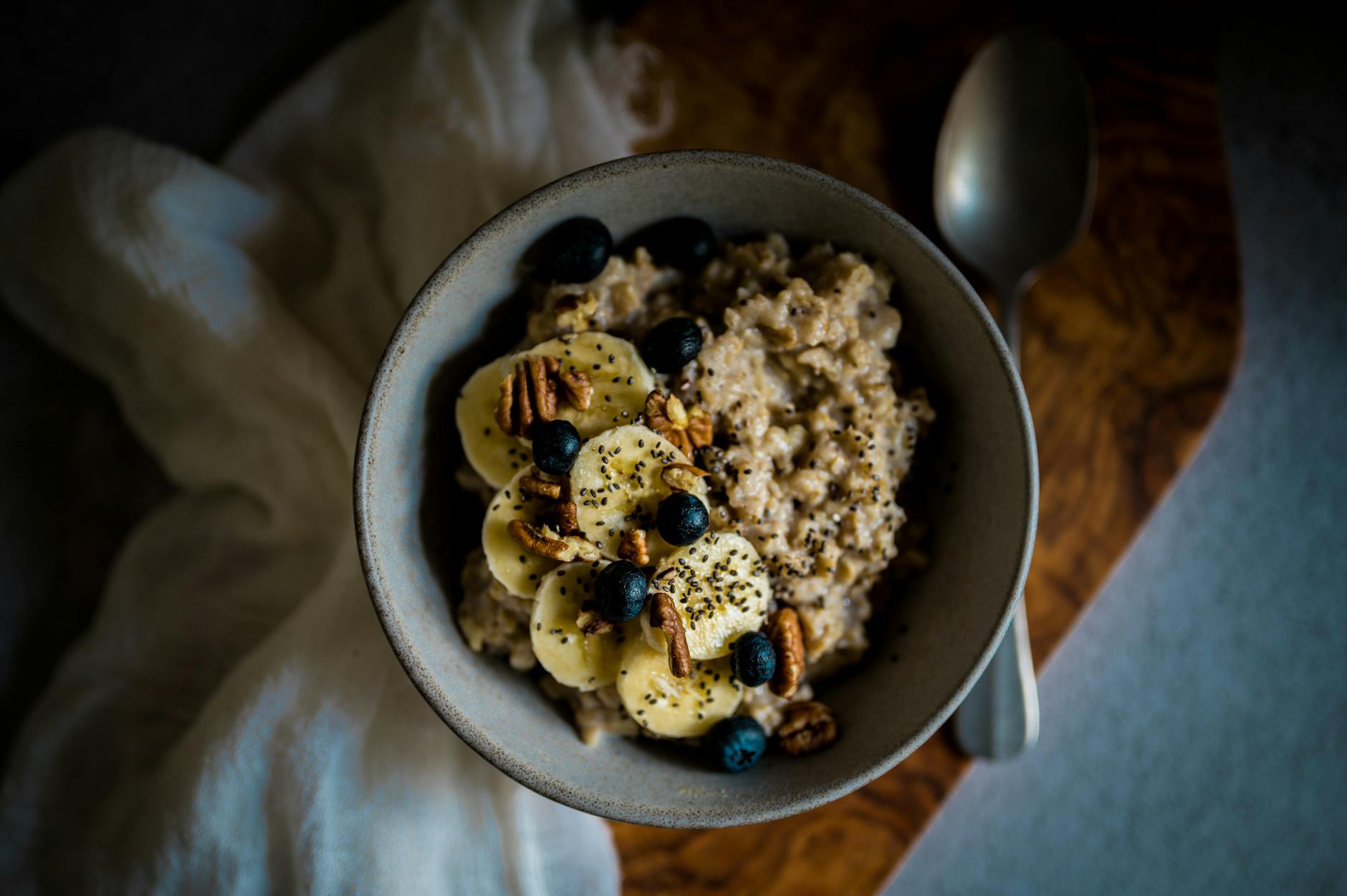 Delicious oatmeal topped with bananas, blueberries, pecans, and chia seeds in a cozy setting.