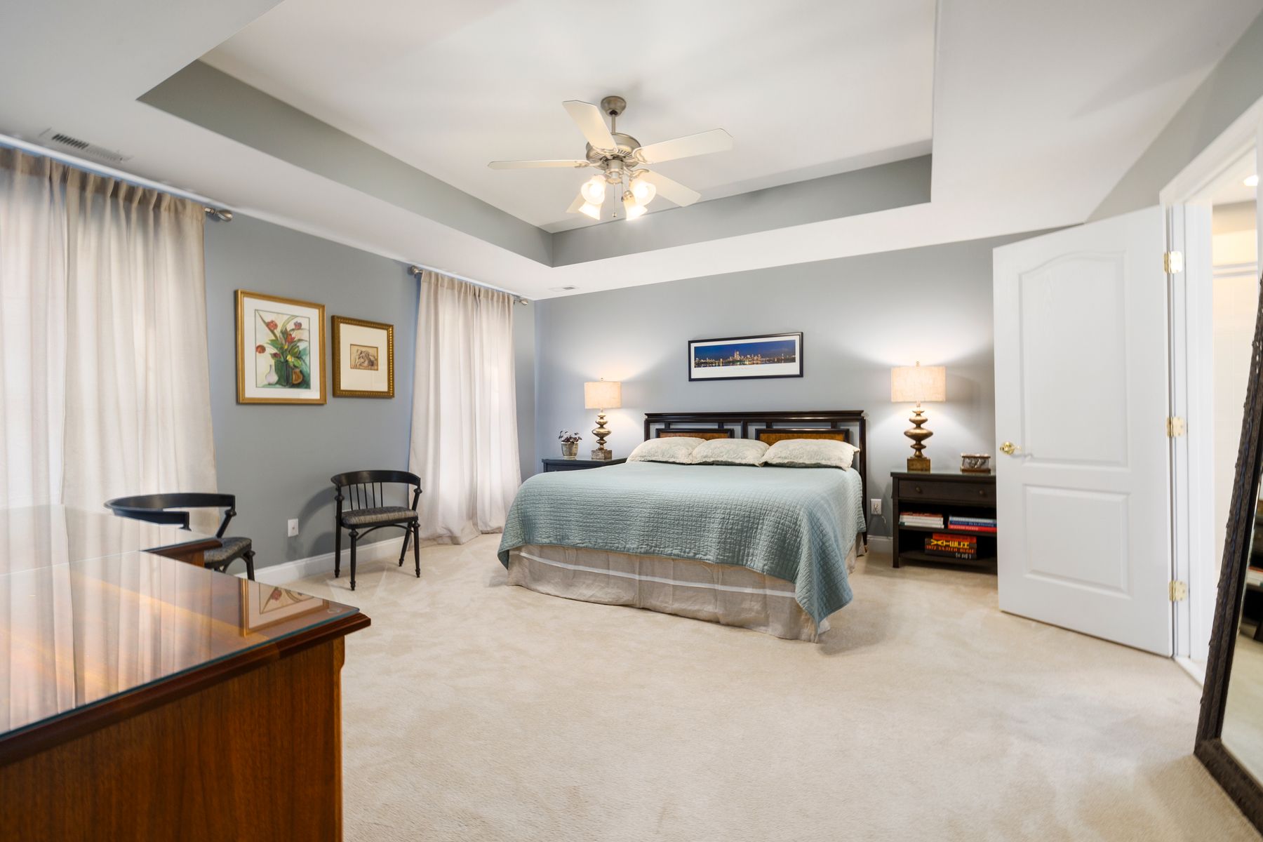 Neutral bed grounded by a broad soft rug that extends around both sides and the foot
