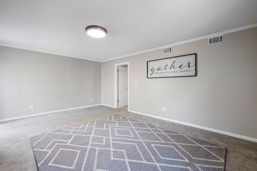 Spacious minimalistic room with gray walls, carpet, and wall art. Perfect for showcasing interior design.