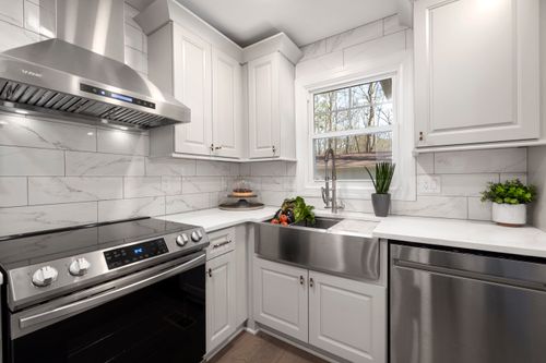 Free Stylish white kitchen featuring a stainless steel oven, sink, and range hood. Bright and contemporary design. Stock Photo