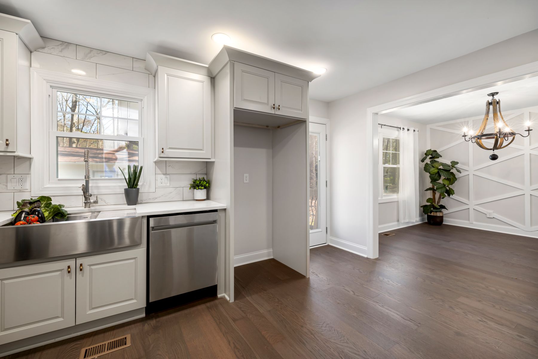 Bright modern kitchen with white cabinetry, stainless-steel appliances and broad wooden flooring