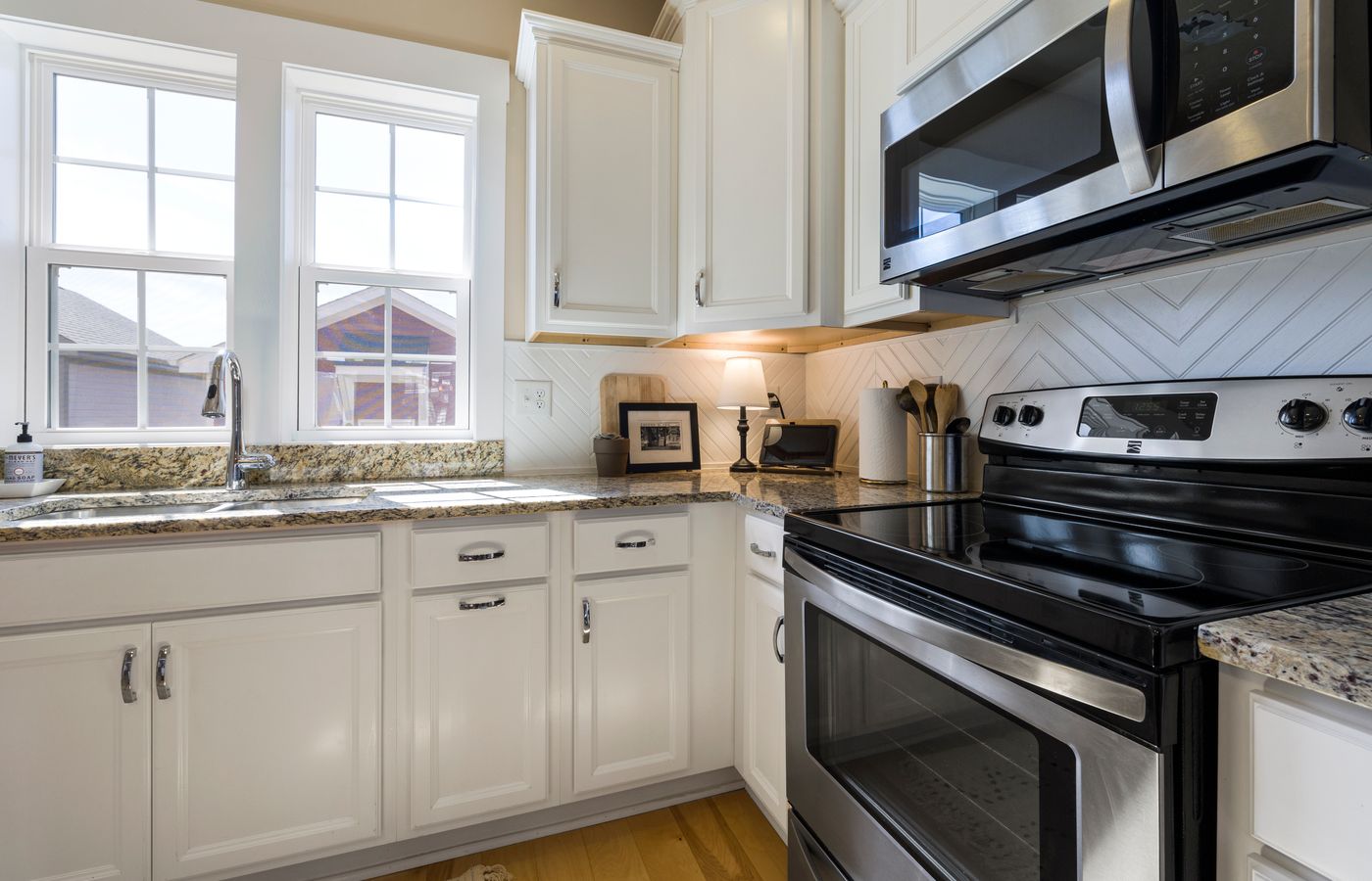 Bright and stylish modern kitchen featuring white cabinets and granite countertops with stainless steel appliances.