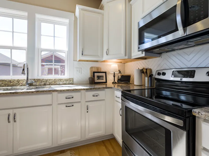 Bright modern kitchen with white cabinets, granite counters and steel appliances Bright modern kitchen with white cabinets, granite counters and steel appliances