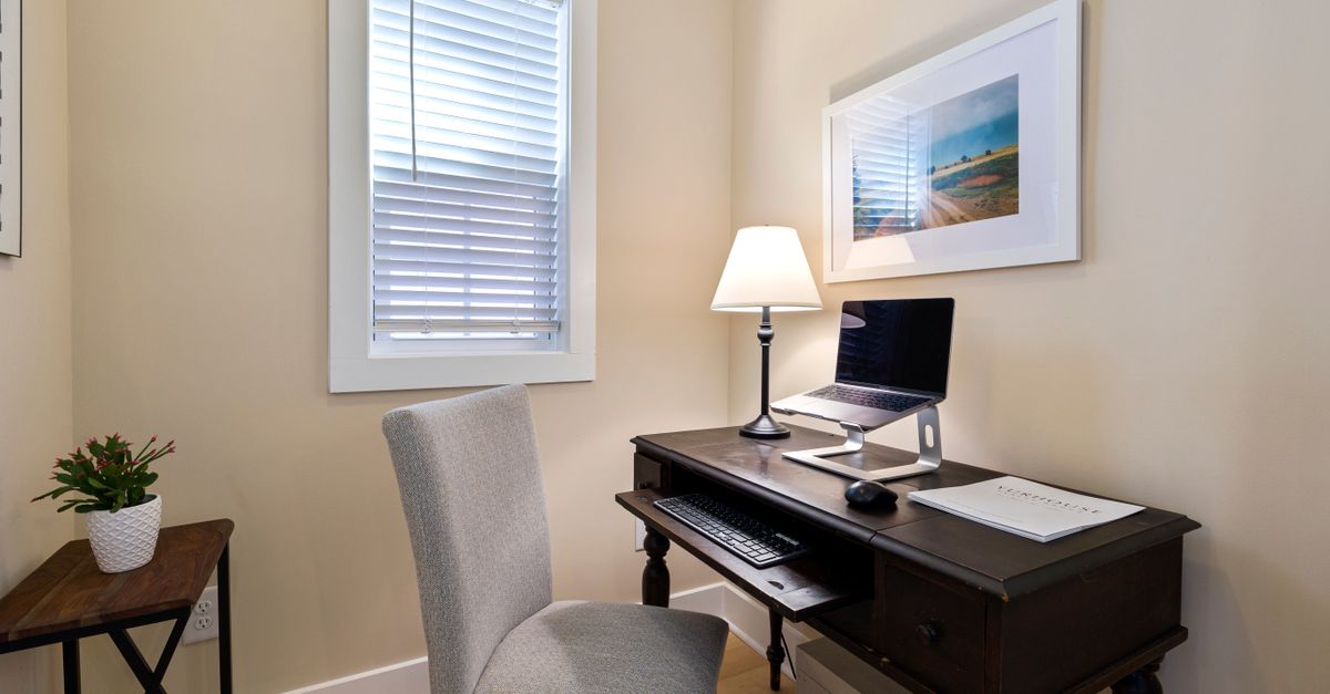 A tidy home office space with a wooden desk, laptop, and ambient lighting. Perfect for remote work.