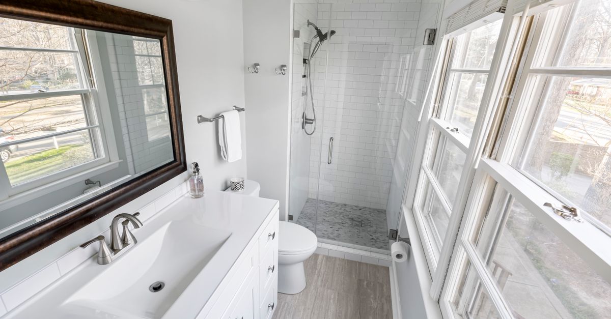 Contemporary minimalist bathroom featuring a tiled shower, vanity, and ample natural light.