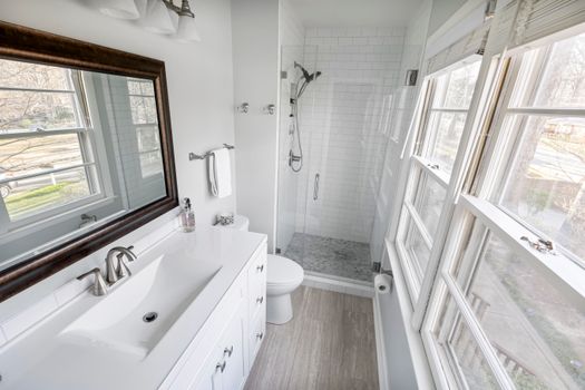 Contemporary minimalist bathroom featuring a tiled shower, vanity, and ample natural light.