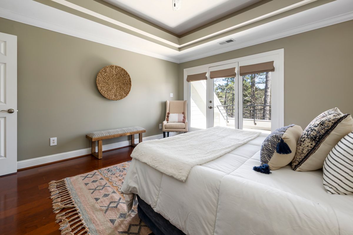 Sunlit Hamptons bedroom with white bedding and warm wood details