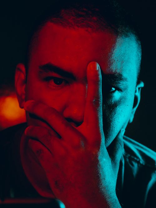 Free Moody portrait of a man in red and blue lighting with a thoughtful pose. Stock Photo