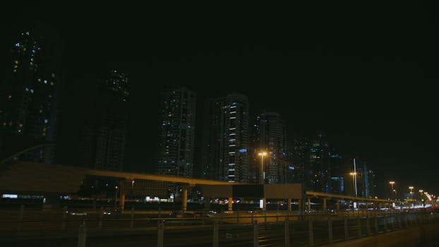 Moody cityscape of skyscrapers at night with illuminated streets and dark sky.