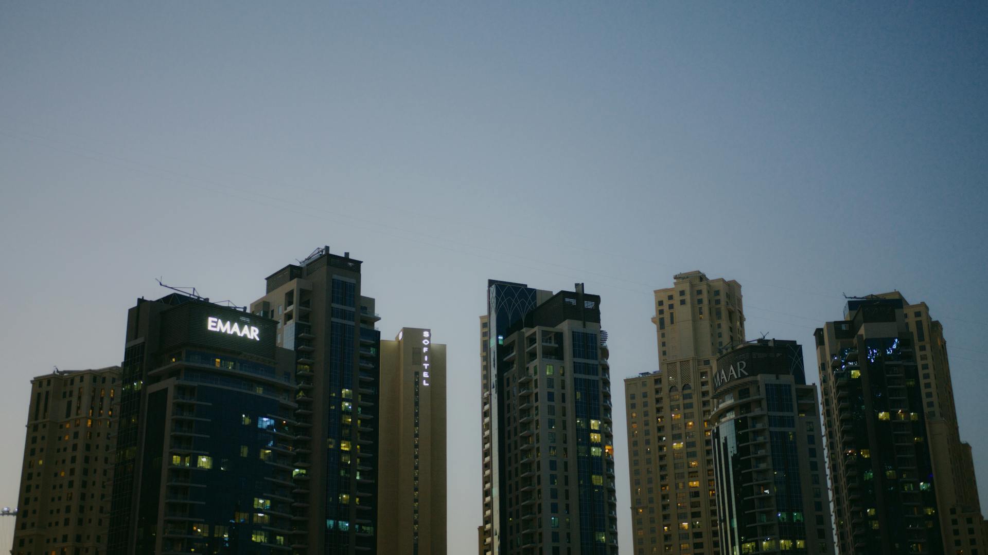 Skyline of modern skyscrapers with EMAAR buildings at dusk, showcasing urban architecture.