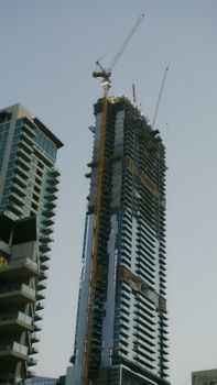 High-rise building under construction with a crane against a clear sky.