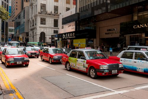 Free Bustling city street with red taxis and busy shops in downtown on a sunny day. Stock Photo