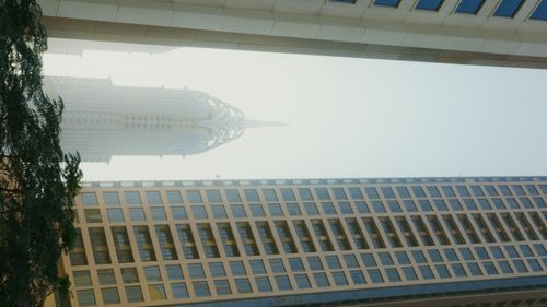 Free Architectural reflection of a modern skyscraper in a window facade, under a clear sky. Stock Photo