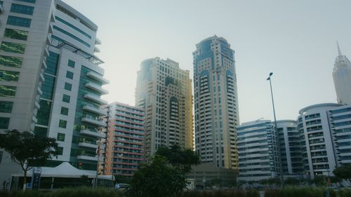 Free Dynamic cityscape featuring high-rise buildings under a blue sky, capturing modern urban architecture. Stock Photo