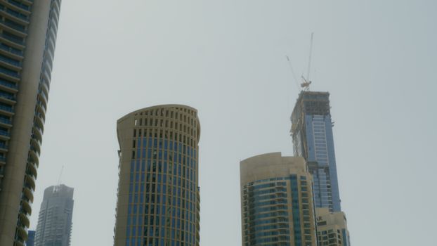 Low-angle shot of modern skyscrapers under construction against a clear sky in Dubai.