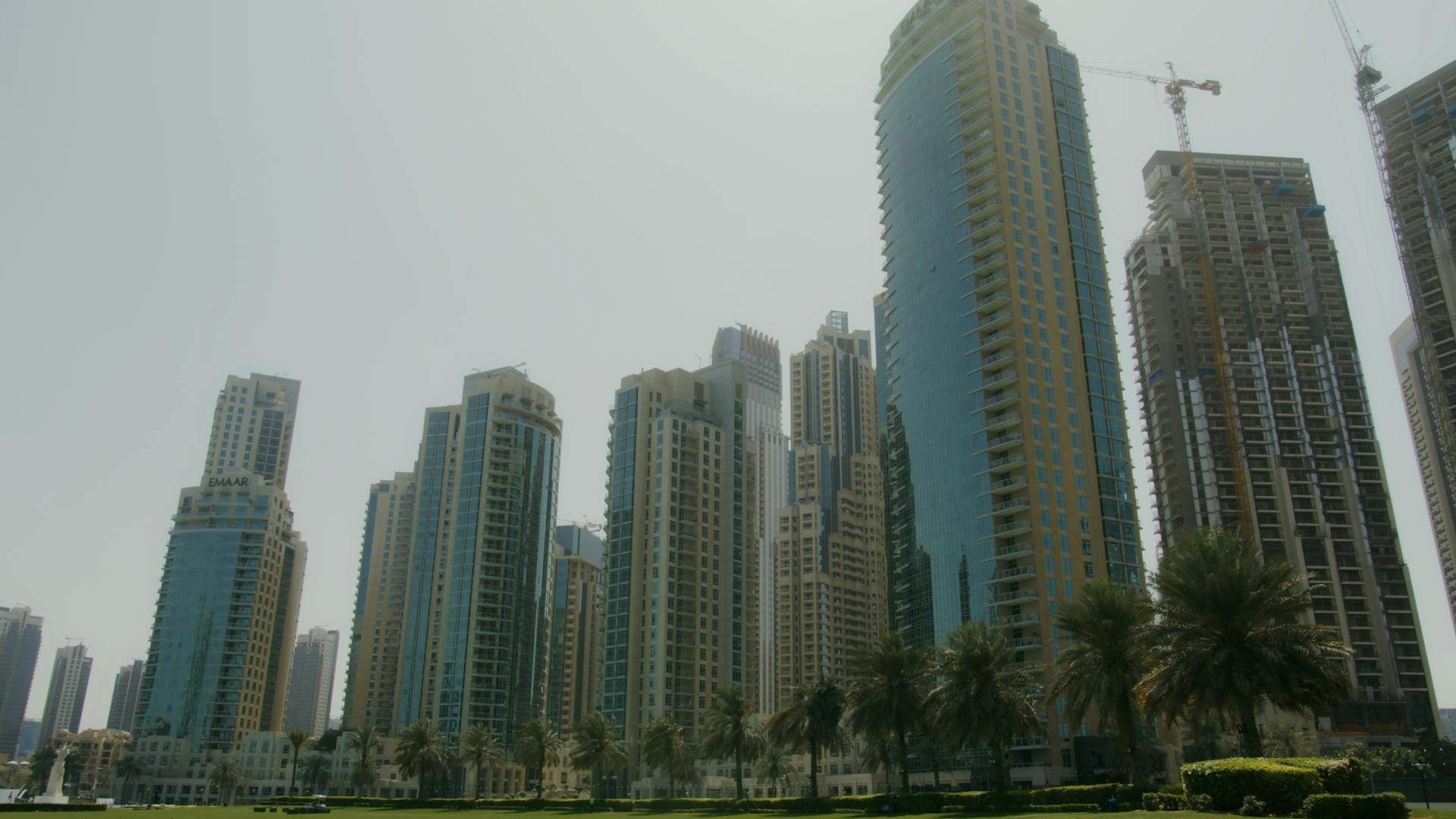 Tall modern skyscrapers rise against a clear blue sky in a vibrant Dubai cityscape.