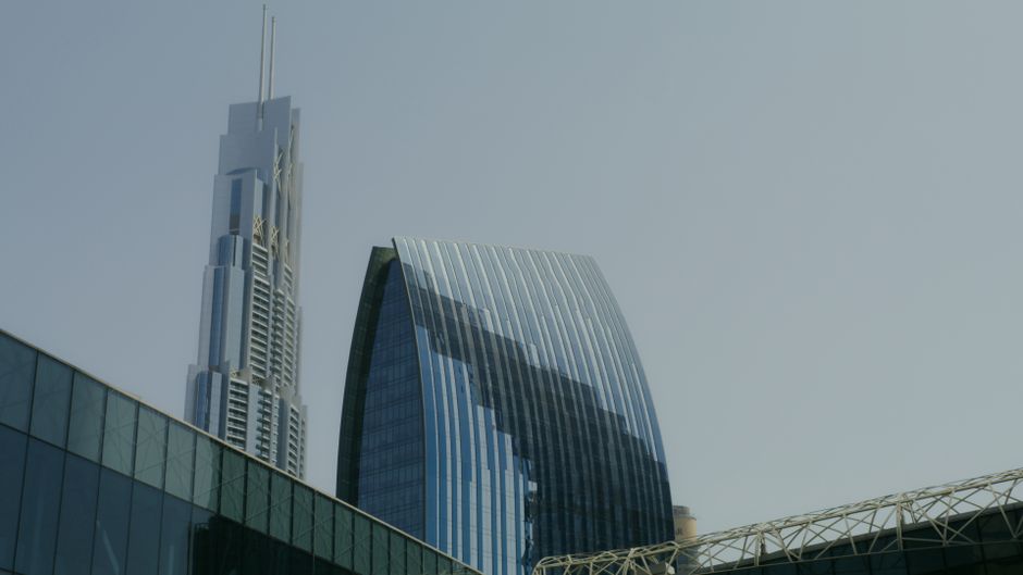 Low-angle view of modern Dubai skyscrapers with glass facades against a clear sky.