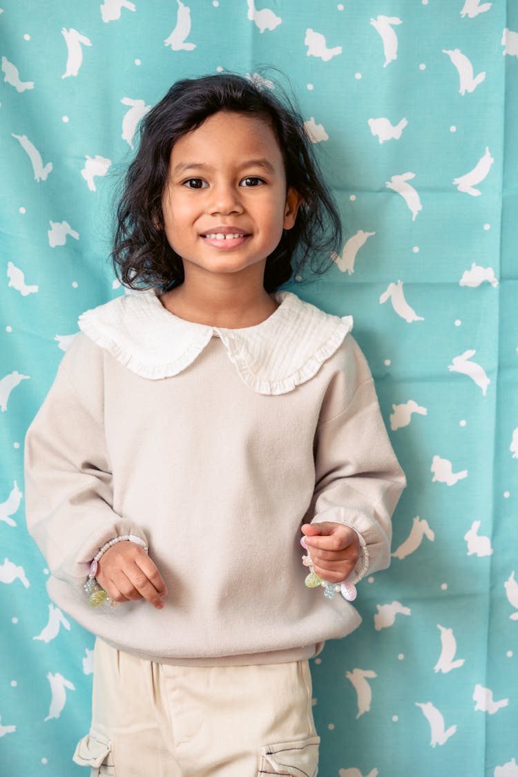 Smiling Ethnic Girl Against Fabric With Rabbit Ornament