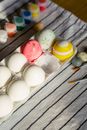 From above of bright eggs with ornament between paints and paintbrushes on fabric during festive occasion in sunlight