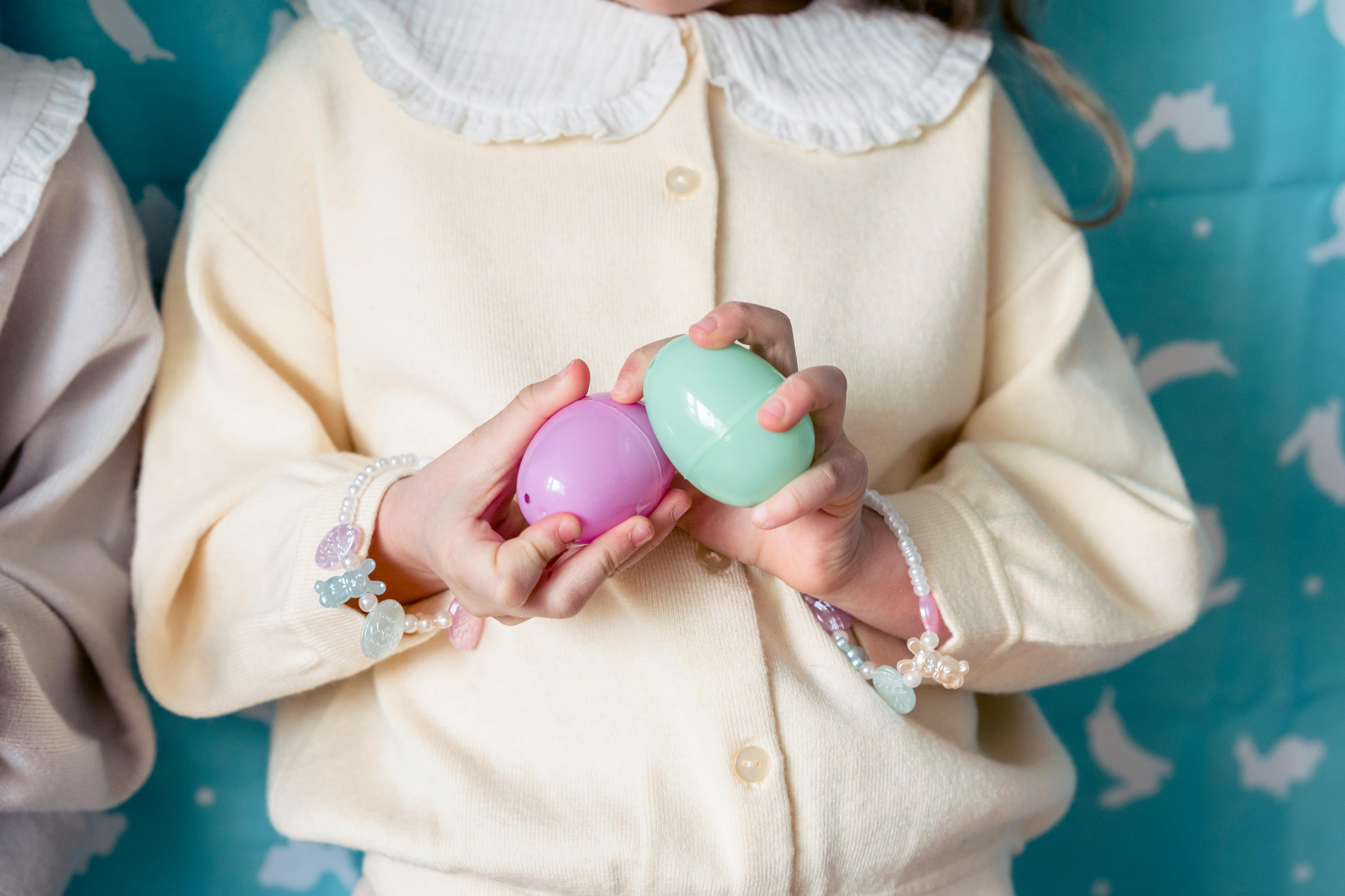 crop faceless girl playing with toy eggs