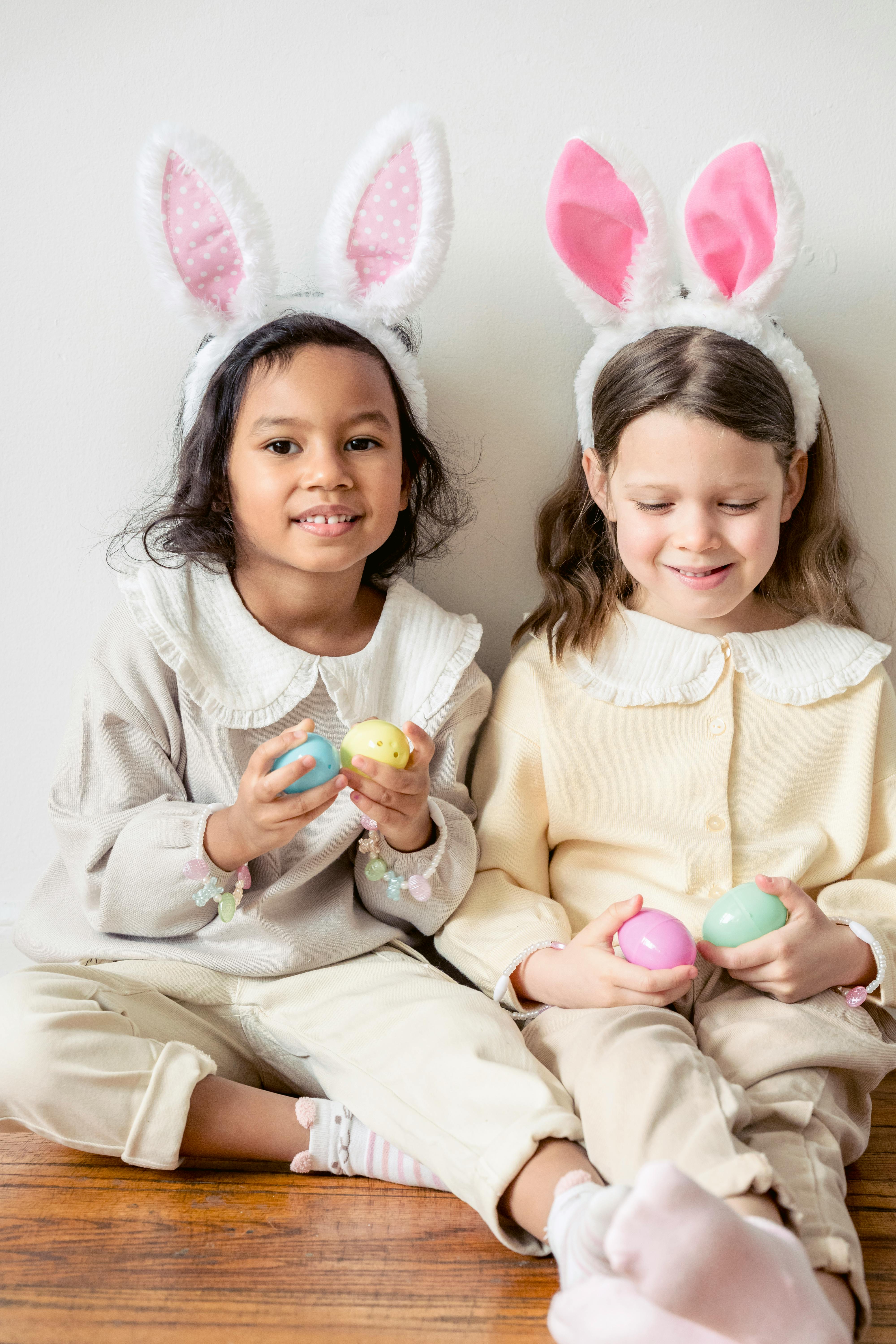 girls in bunny ears sitting on floor with toy eggs