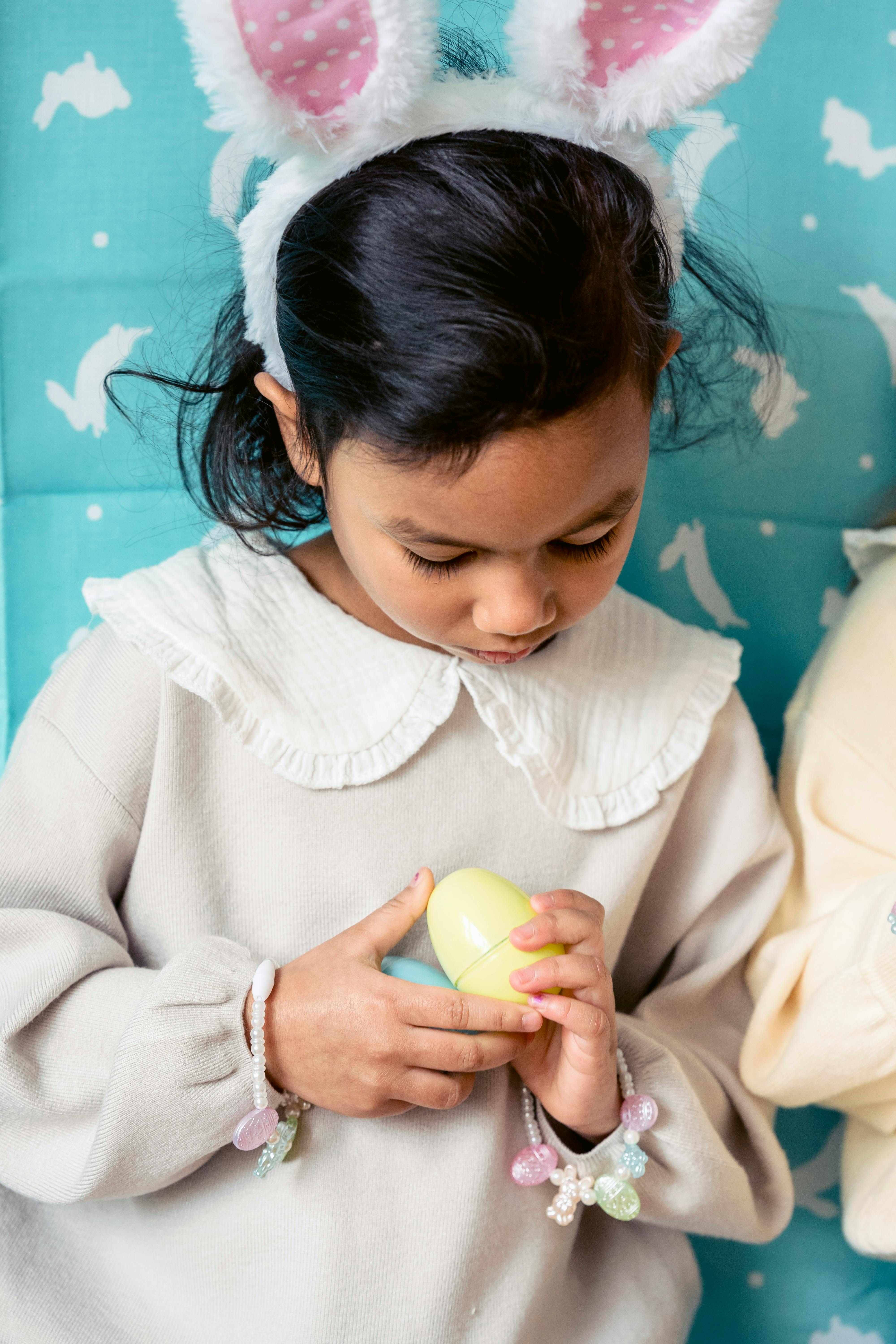 cute ethnic girl playing with toy egg