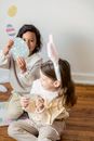 Cute diverse girls playing with Easter stickers on floor