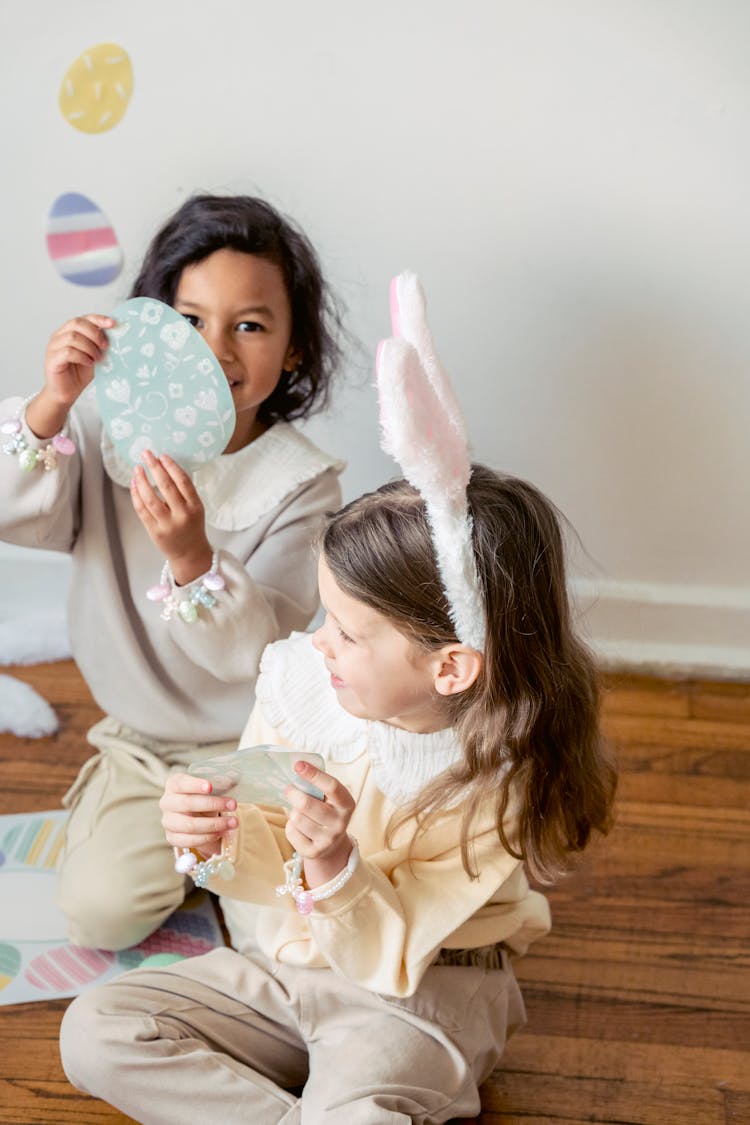 Cute Diverse Girls Playing With Easter Stickers On Floor