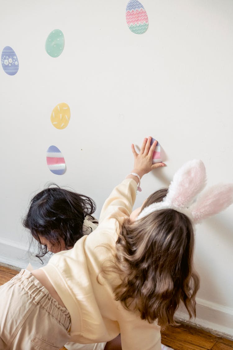 Unrecognizable Little Girls Applying Easter Stickers On Wall